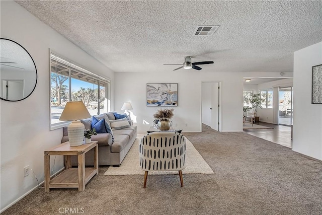 carpeted living room with a textured ceiling and ceiling fan