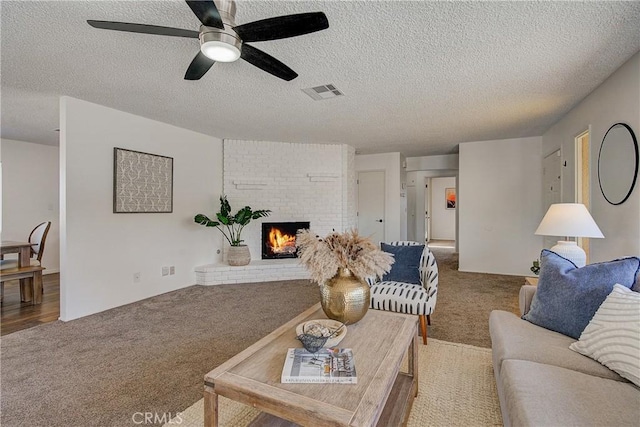 living room featuring a fireplace, carpet, and a textured ceiling