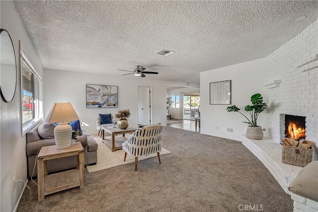 living room with ceiling fan, carpet, a textured ceiling, and a brick fireplace