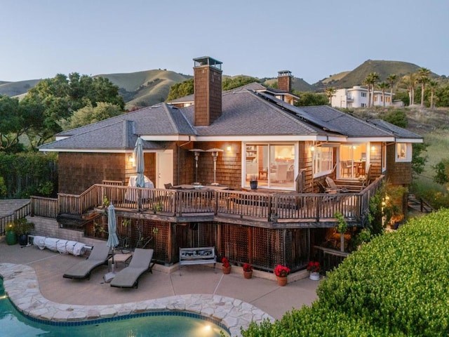 back of property featuring a swimming pool side deck with mountain view and a patio