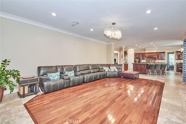 living room with light hardwood / wood-style floors, ornamental molding, and an inviting chandelier