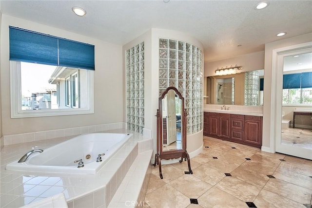 bathroom with tile patterned floors, vanity, and a relaxing tiled tub