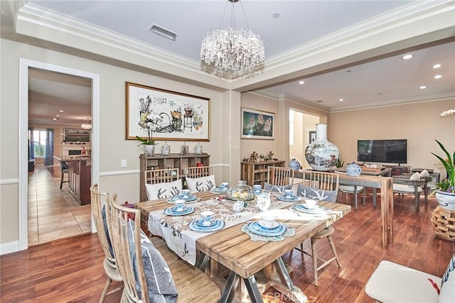 dining area featuring hardwood / wood-style floors, an inviting chandelier, and crown molding