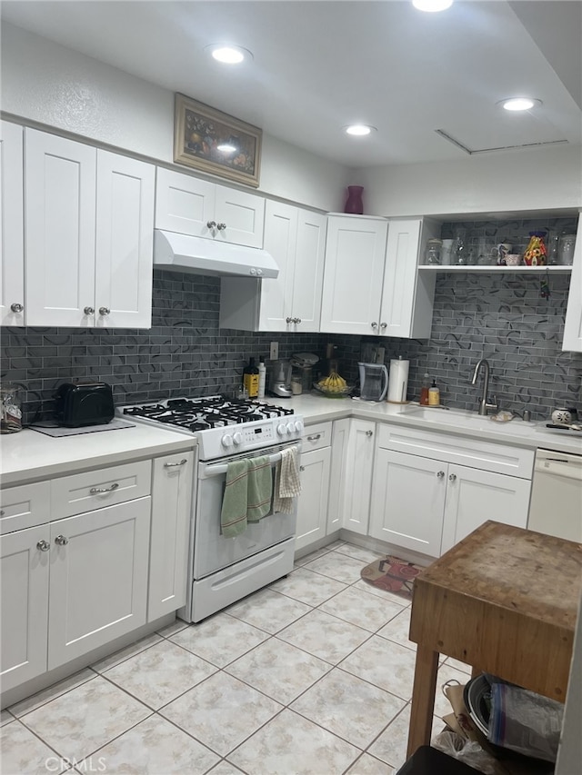 kitchen featuring backsplash, white appliances, sink, light tile patterned floors, and white cabinets