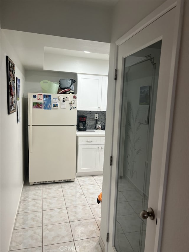 kitchen with decorative backsplash, white refrigerator, white cabinetry, and light tile patterned flooring