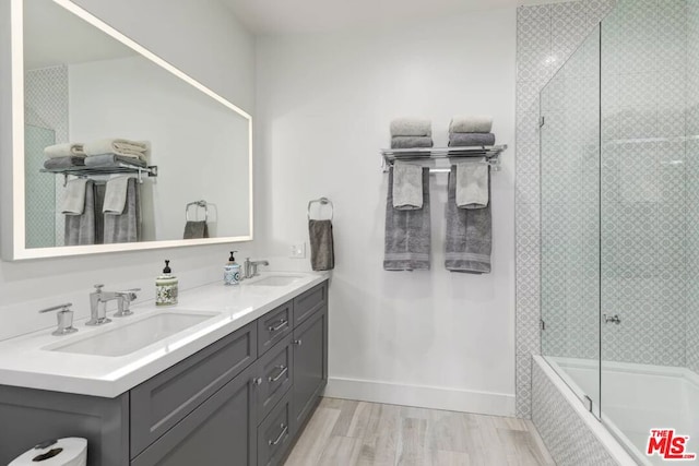 bathroom with double vanity and combined bath / shower with glass door