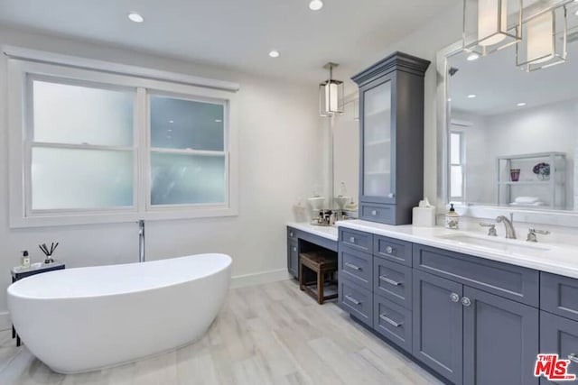 bathroom with hardwood / wood-style floors, a bath to relax in, and vanity