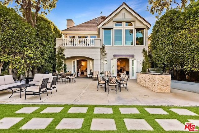 back of property with a patio area, an outdoor kitchen, and a balcony