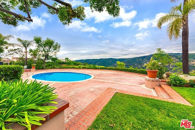 view of swimming pool featuring a patio and a mountain view