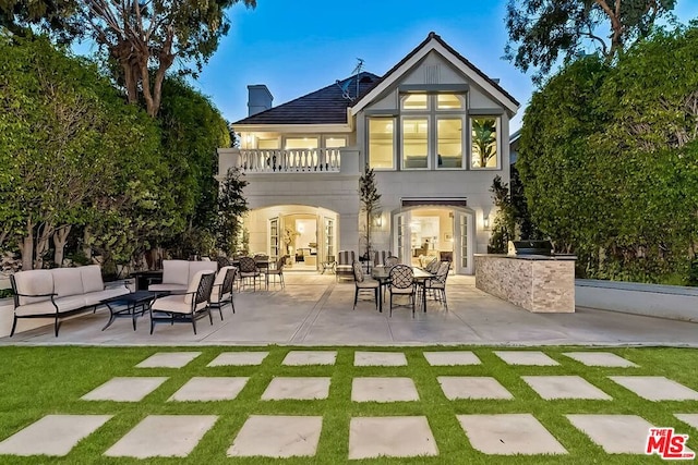 rear view of house featuring a patio area, exterior kitchen, a balcony, and outdoor lounge area