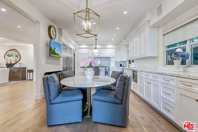 dining space with a chandelier and light hardwood / wood-style floors