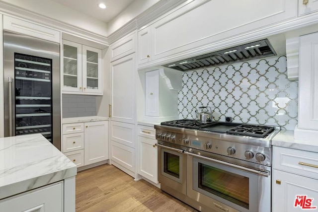 kitchen with light hardwood / wood-style floors, light stone counters, beverage cooler, backsplash, and double oven range