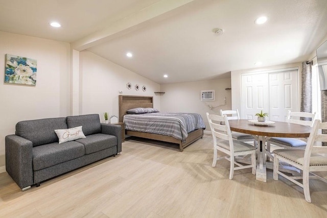 bedroom featuring lofted ceiling with beams, light wood-type flooring, an AC wall unit, and a closet