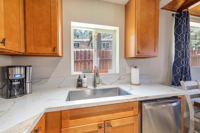 kitchen with light stone counters, stainless steel dishwasher, and sink