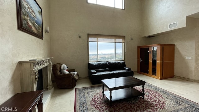 living room featuring tile floors, a fireplace, and a high ceiling