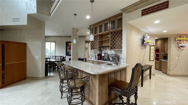 kitchen featuring a kitchen breakfast bar, hanging light fixtures, light tile flooring, and light stone countertops