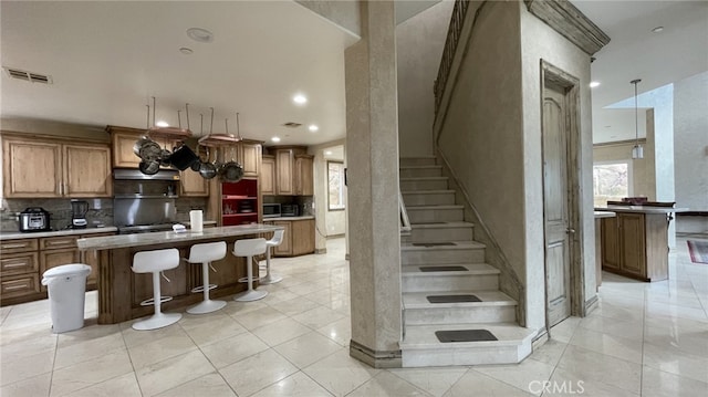 kitchen with fume extractor, backsplash, light tile floors, a center island, and a breakfast bar