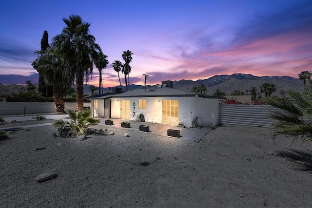 back house at dusk with a mountain view and a patio