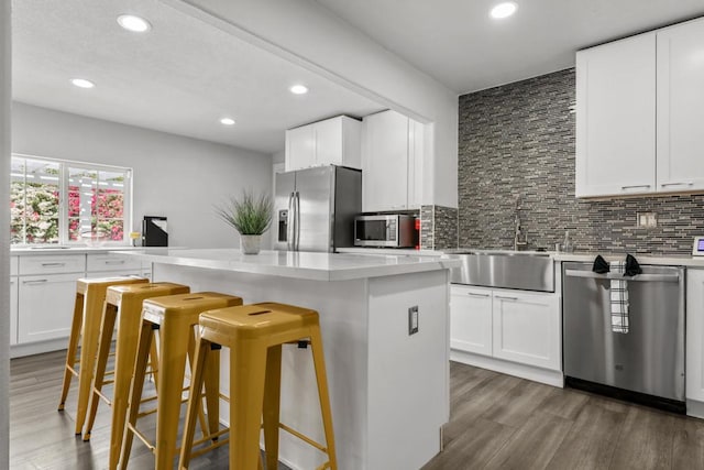 kitchen featuring white cabinetry, sink, dark wood-type flooring, a kitchen bar, and appliances with stainless steel finishes