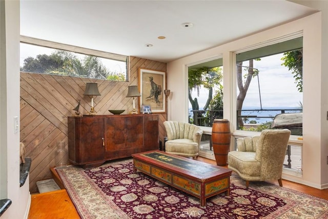 sitting room with hardwood / wood-style floors and wooden walls