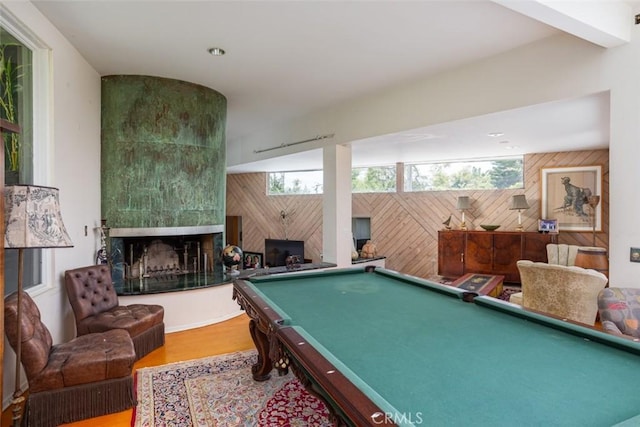 recreation room with hardwood / wood-style flooring, pool table, a fireplace, and wood walls