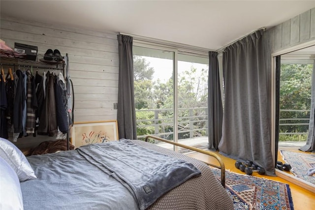 bedroom featuring hardwood / wood-style flooring, wooden walls, and a closet