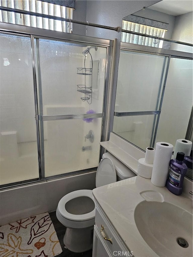 full bathroom featuring toilet, vanity, and shower / bath combination with glass door