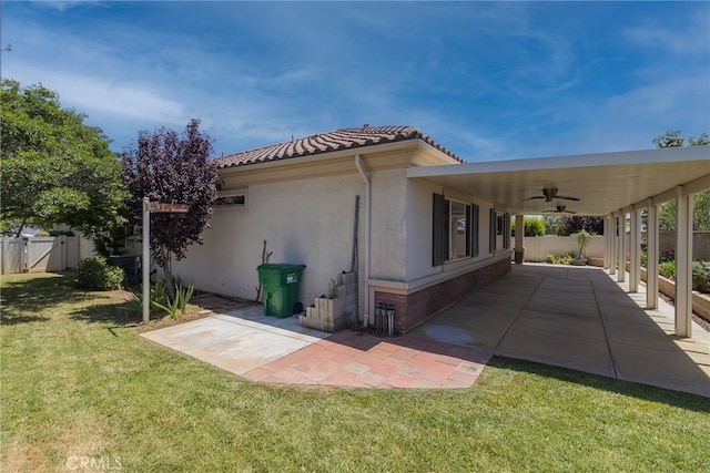 view of home's exterior featuring ceiling fan, a yard, and a patio