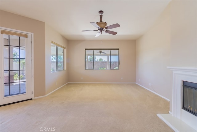 unfurnished living room featuring light carpet, a wealth of natural light, and ceiling fan