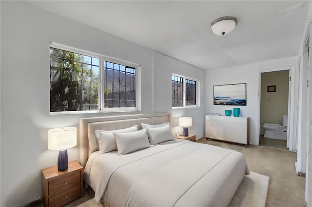 bedroom with light colored carpet and ensuite bath