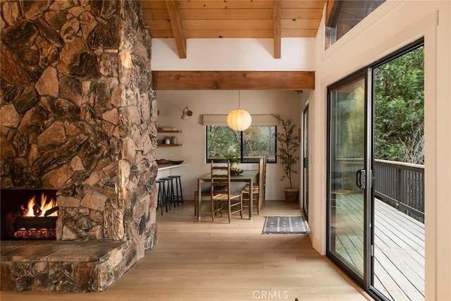 interior space with a stone fireplace, wooden ceiling, a healthy amount of sunlight, and light hardwood / wood-style floors