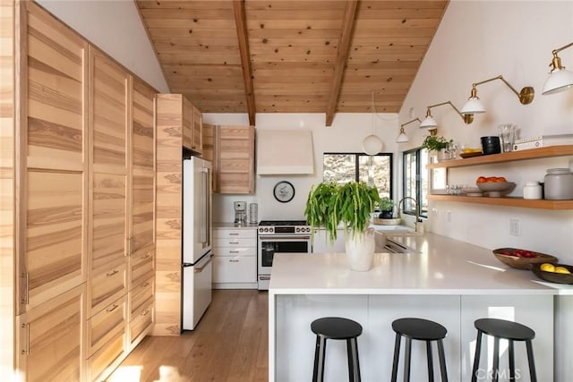 kitchen featuring vaulted ceiling with beams, a breakfast bar, light wood-type flooring, and appliances with stainless steel finishes