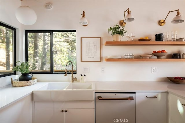 kitchen with white cabinets, decorative light fixtures, stainless steel dishwasher, and sink