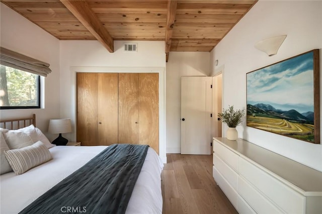 bedroom with beam ceiling, light hardwood / wood-style floors, a closet, and wooden ceiling