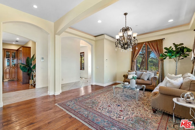 living room featuring light wood-type flooring, beam ceiling, and a notable chandelier