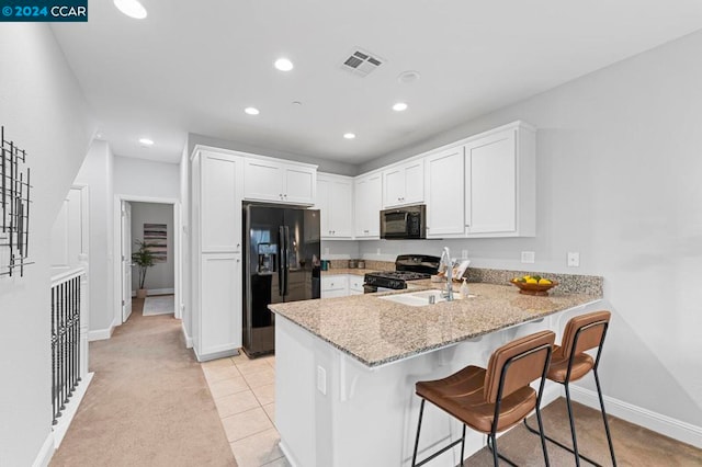 kitchen featuring sink, a kitchen bar, kitchen peninsula, and black appliances