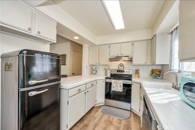 kitchen with white cabinetry, sink, tile counters, stainless steel appliances, and light hardwood / wood-style flooring