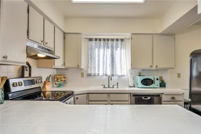 kitchen with sink, backsplash, tile counters, and stainless steel appliances