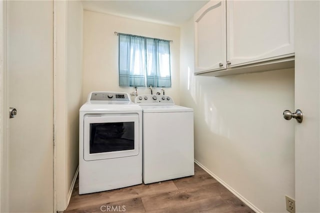 clothes washing area featuring cabinets, washing machine and dryer, and light wood-type flooring