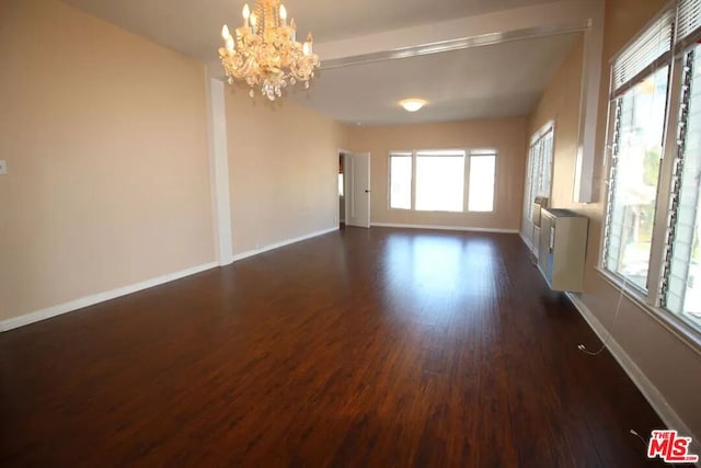 spare room with plenty of natural light, an inviting chandelier, and dark wood-type flooring