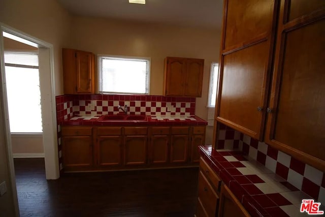 kitchen featuring plenty of natural light, tasteful backsplash, dark wood-type flooring, tile countertops, and sink