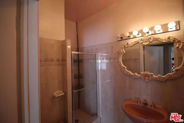 bathroom with walk in shower, tile walls, and sink