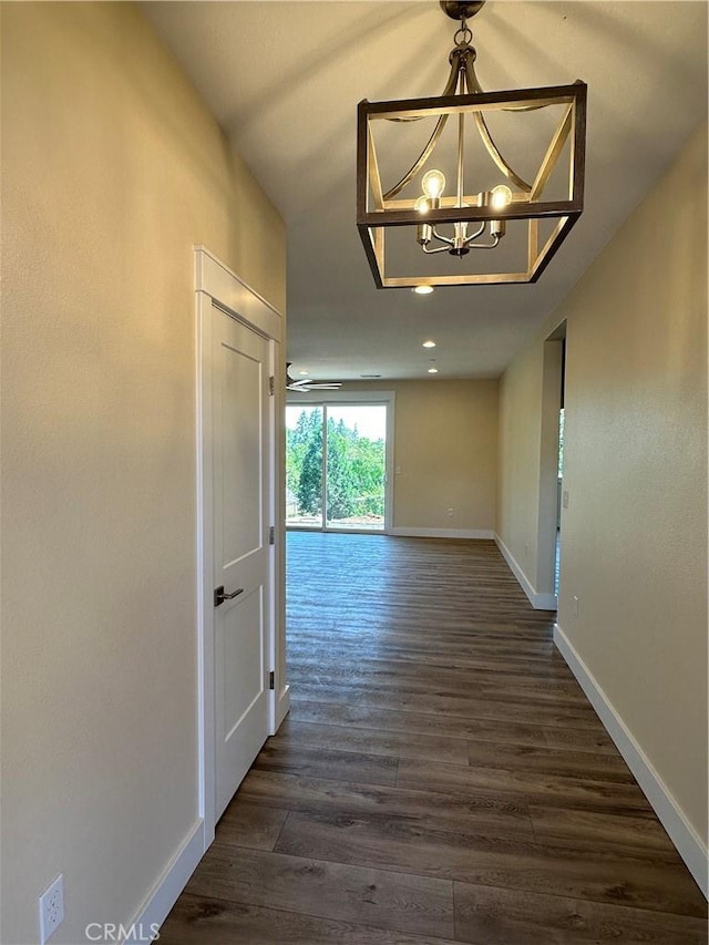 hallway featuring dark wood-type flooring and a chandelier