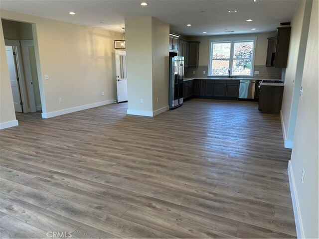 kitchen featuring decorative light fixtures, stainless steel dishwasher, hardwood / wood-style floors, black refrigerator with ice dispenser, and backsplash