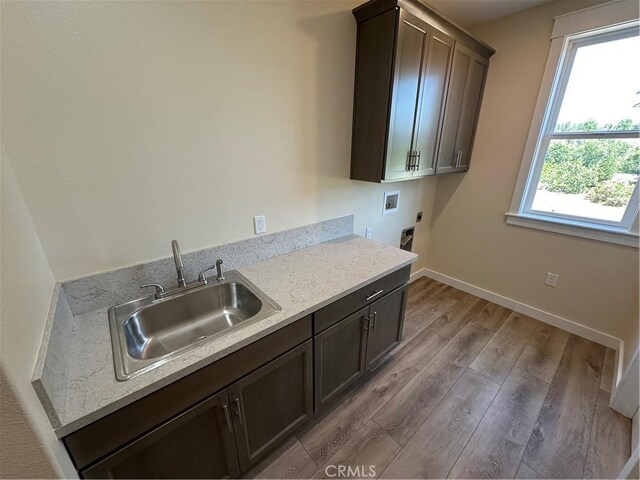 kitchen with sink, light stone countertops, hardwood / wood-style floors, and dark brown cabinetry