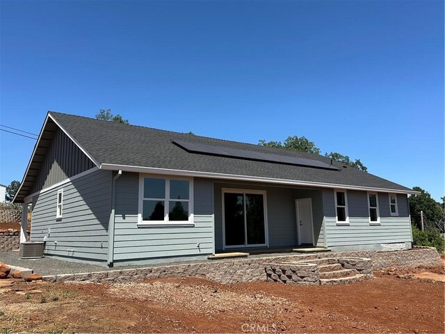 ranch-style home featuring solar panels and central air condition unit