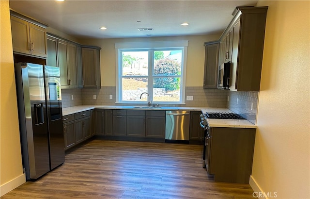 kitchen featuring dark wood-type flooring, backsplash, appliances with stainless steel finishes, and sink