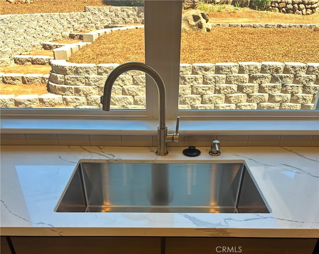 interior details featuring sink and light stone countertops