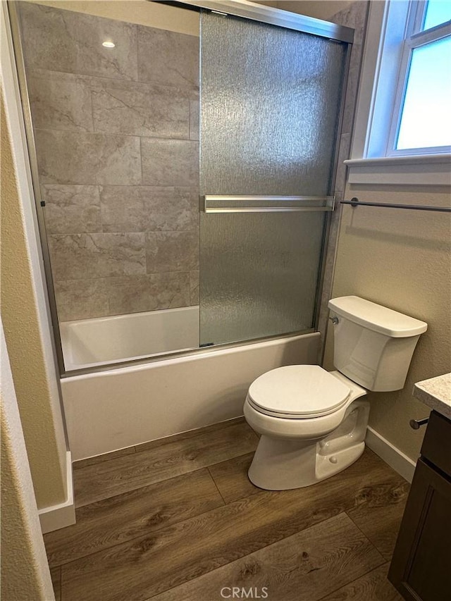 full bathroom with vanity, hardwood / wood-style flooring, shower / bath combination with glass door, and toilet