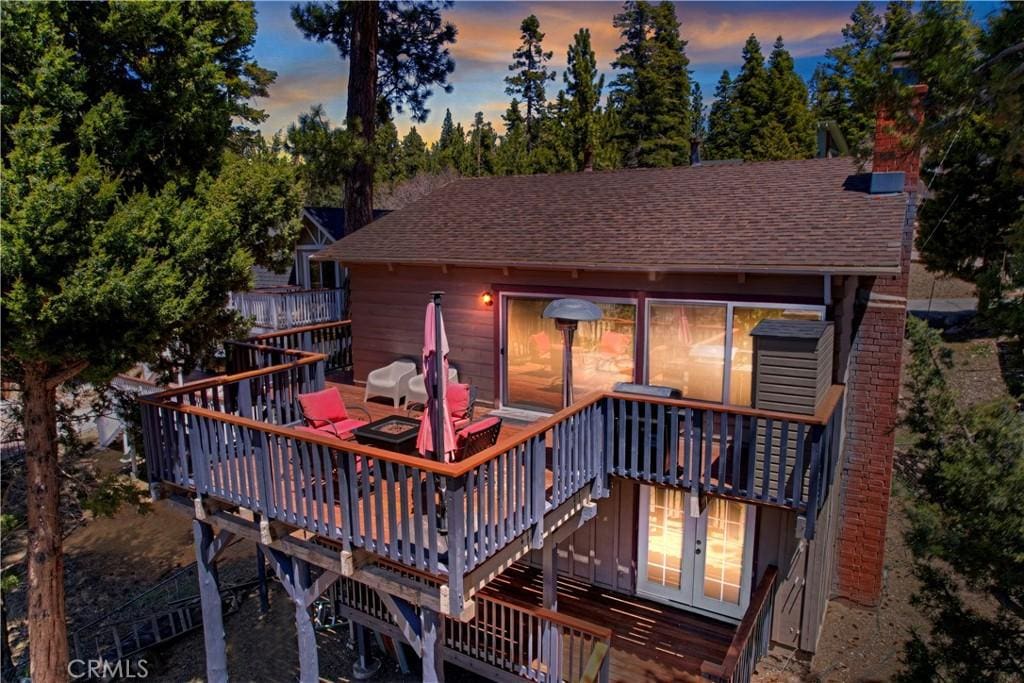 back house at dusk featuring a deck and french doors